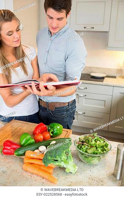 Couple reading cookery book in kitchen
