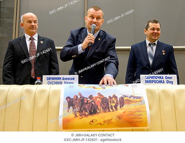 Expedition 47 Russian cosmonaut Alexei Ovchinin of Roscosmos, center, describes a poster created for him and his fellow crew members