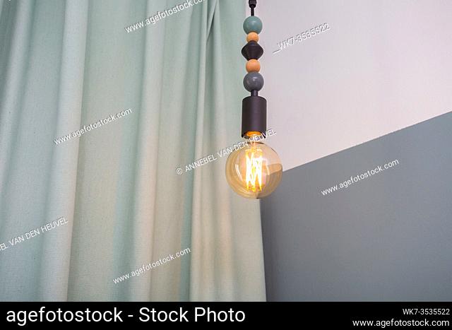 hanging light bulb lamp in room near blue curtains, modern interior scandinavian design closeup