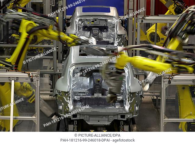 13 December 2018, Saxony, Leipzig: Several welding robots are working on a body of a Porsche Macan in the body shop in Leipzig