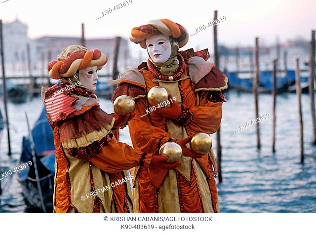 Couple with carnival costume and mask holding balls at the promenade of Piazza San Marco and Canale di San Marco