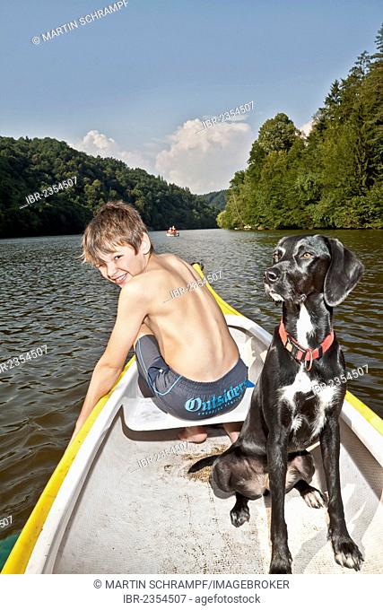 Boy sitting in a canoe with his hunting dog, mongrel