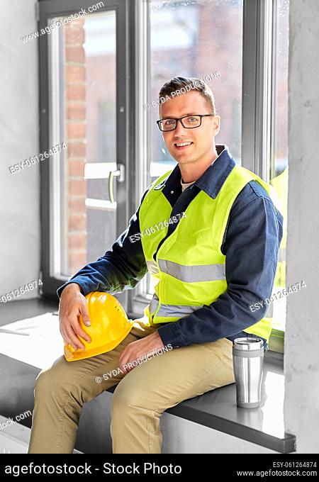 happy builder with tumbler sitting on window sill