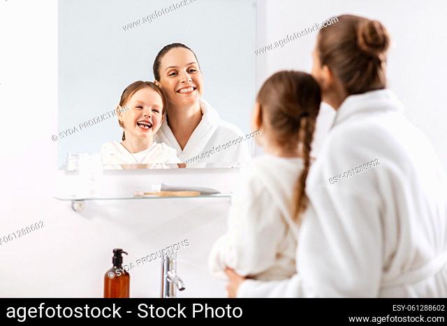 mother and daughter looking to mirror in bathroom