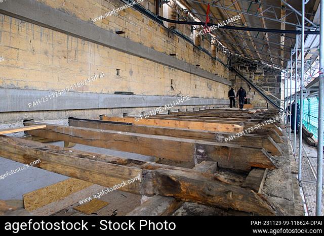 29 November 2023, Saxony-Anhalt, Hamersleben: Workers stand on the beams of the roof truss of the collegiate church of St. Pankratius