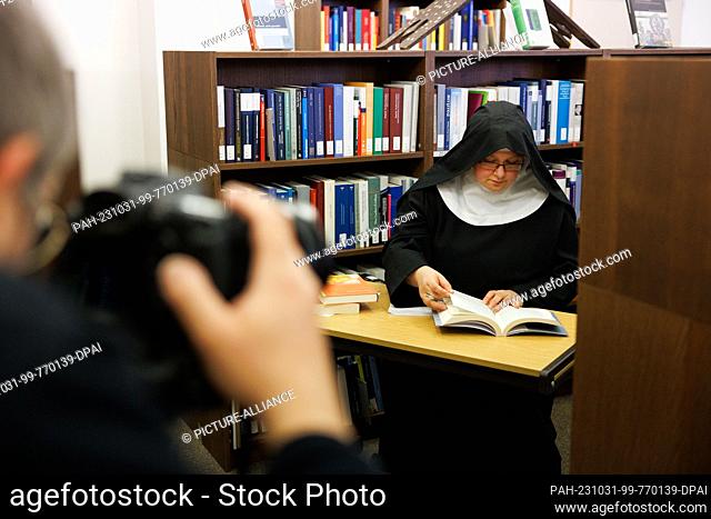 PRODUCTION - 20 October 2023, Lower Saxony, Osnabrück: Sister Josefine sits in a posed situation in a room of the Osnabrück Diocesan Library