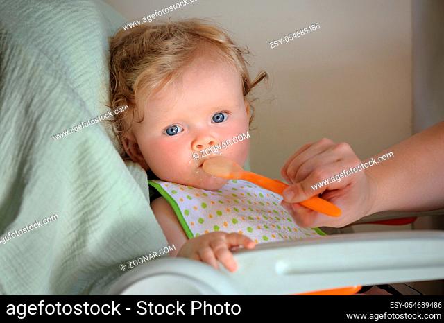 Little cute 9 months old baby girl feeding with spoon
