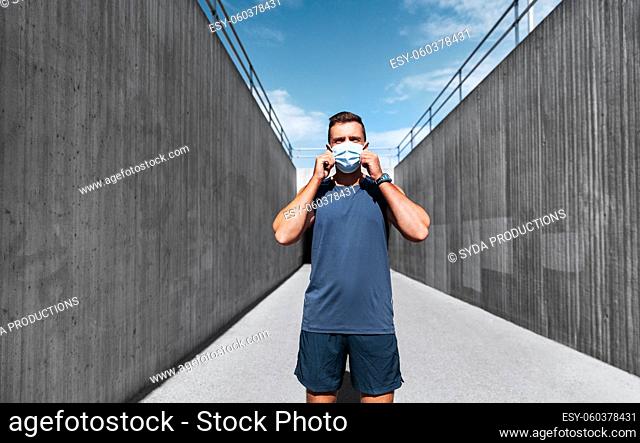 young man in medical mask doing sports outdoors