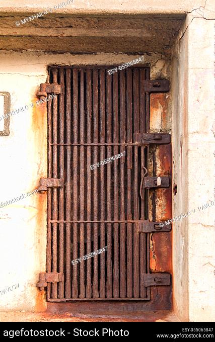 Old rusty door in the form of a thick metal grate