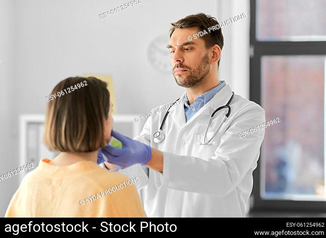 doctor checking lymph nodes of woman at hospital