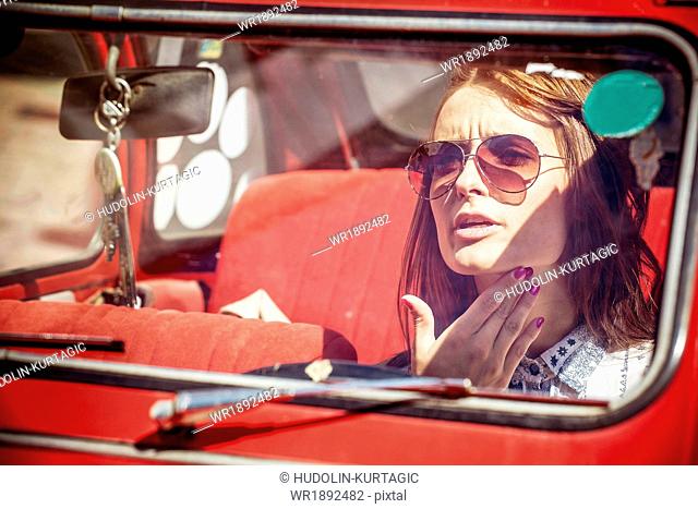 Portrait of young woman with sunglasses in red car
