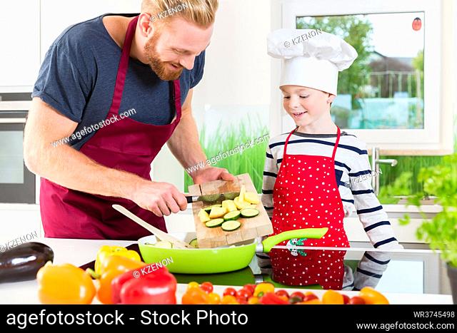 Happy father and son preparing food together in kitchen