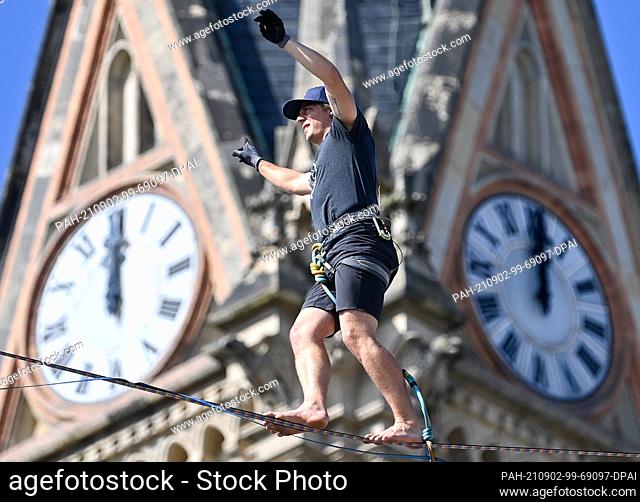 02 September 2021, Saxony, Chemnitz: Peter Bessler balances in front of St. Peter's Church on Theaterplatz in Chemnitz at a height of around 20 meters over a...