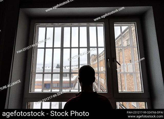 PRODUCTION - 28 November 2023, Hesse, Butzbach: A 57-year-old inmate stands in front of a barred window in Butzbach prison and looks out onto the inner...