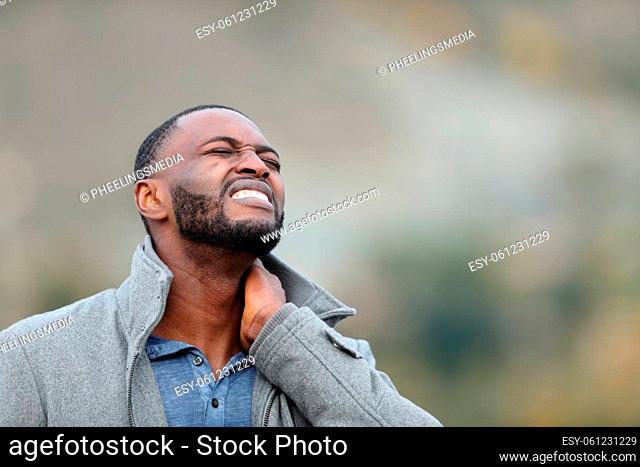 Man with black skin suffering neck ache outdoors in winter