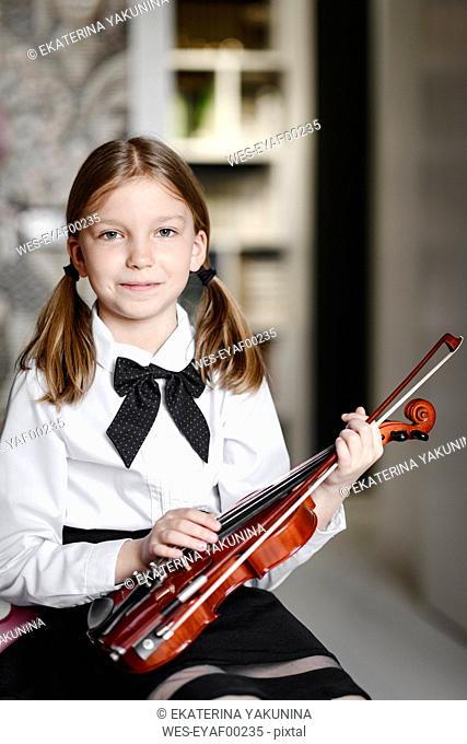 Portrait of a smiling girl with a violin at home