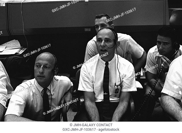 Four members of the prime and backup crews for Apollo 12 monitor activity of the first moon landing mission from consoles in the Mission Control Center in...