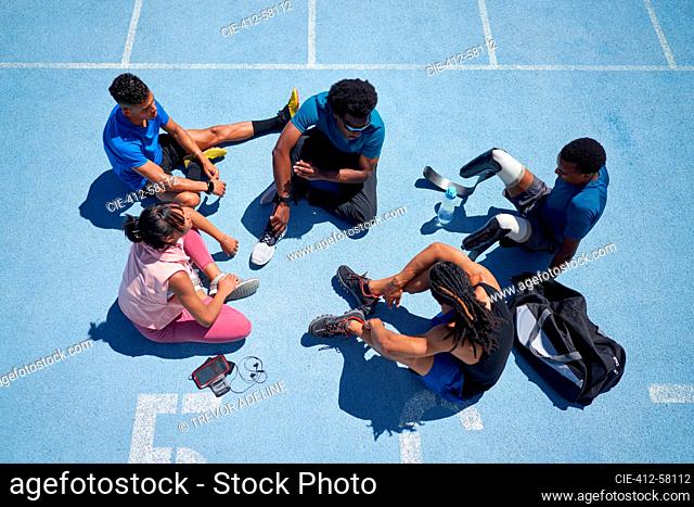 Young athletes talking on sunny blue sports track