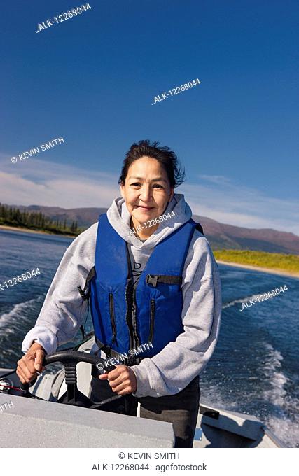 Alaskan Native female driving a motor boat on Kobuk river, Arctic Alaska, summer
