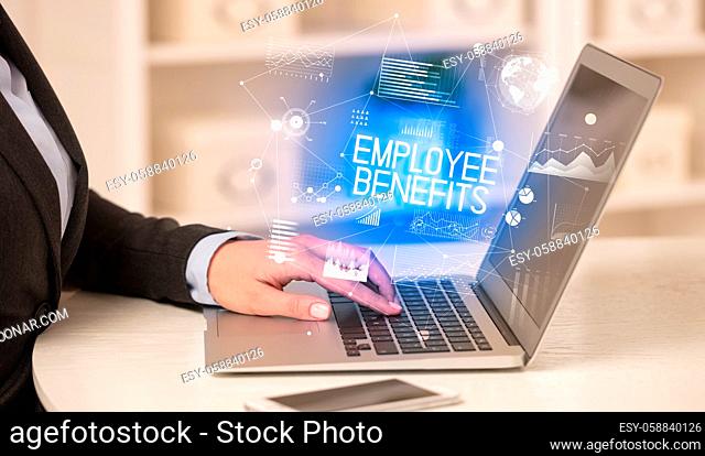 Side view of a business person working on laptop with EMPLOYEE BENEFITS inscription, modern business concept