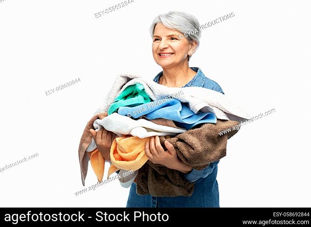 smiling senior woman with heap of bath towels