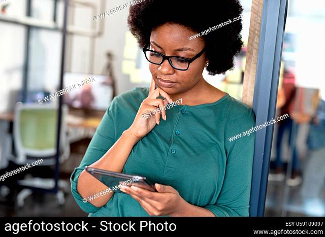 African american businesswoman standing at corridor thinking using digital tablet