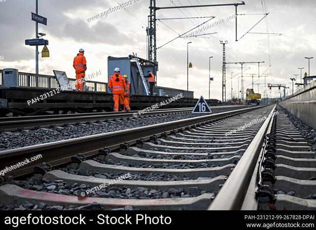 PRODUCTION - 11 December 2023, Bavaria, Eltersdorf: Workers stand in the track bed at the station and dismantle the temporary wooden platform at the railroad...