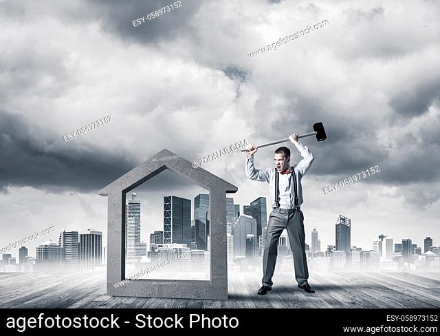 Determined businessman going to break with hammer house concrete figure