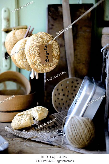 Sesame bagels hanging on a line in a rustic kitchen