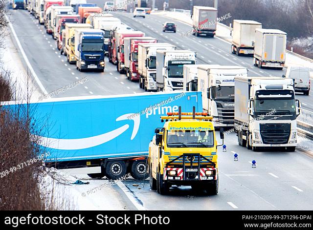 09 February 2021, Lower Saxony, Lehrte: A lorry has slid into the side ditch of the A2 motorway after an accident on slippery roads and is being towed away