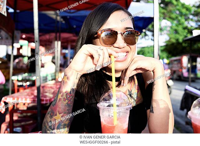Portrait of happy woman drinking a smoothie outdoors