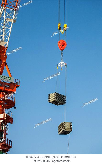 Crane with pulley hook and load at construction site in Kamata, Tokyo, Japan