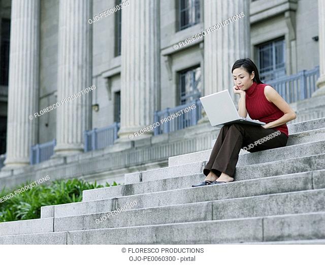 Businesswoman outdoors on staircase with laptop