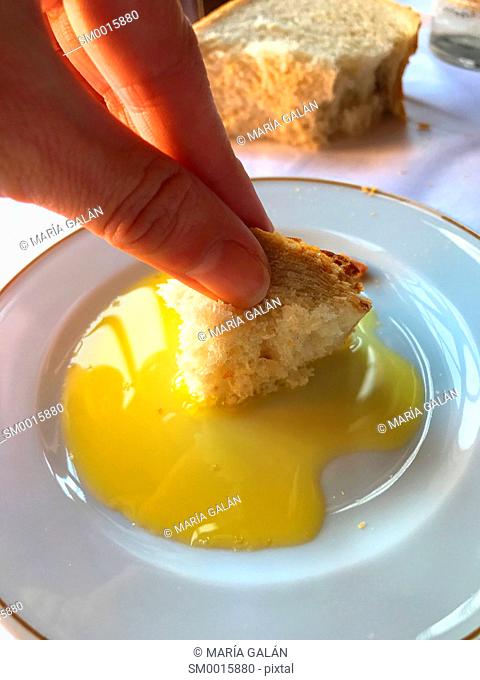 Hand dunking bread in olive oil. Spain