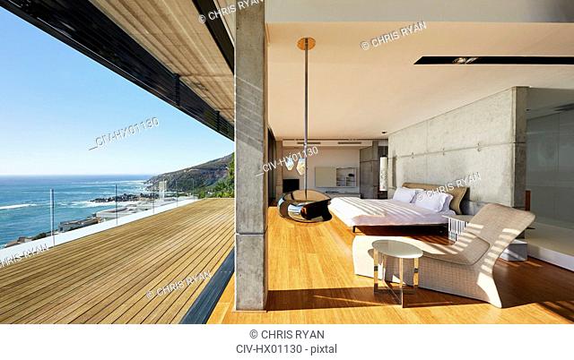 Modern luxury bedroom open to patio with sunny ocean view