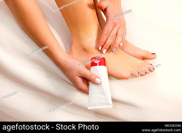 Woman fit girl putting ointment cream on bad injured ankle or applying moisturizer cosmetic cream on foot. Health skin care