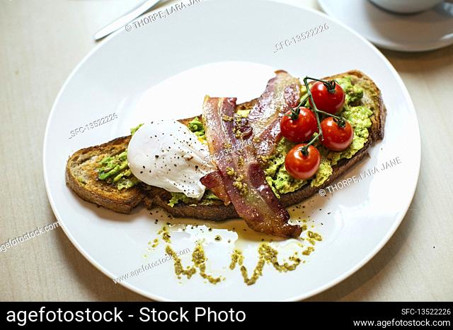 Toasted bread with avocado, bacon, poached egg and tomatoes