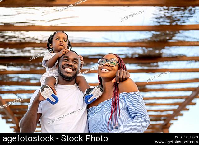 Happy family standing under roofing