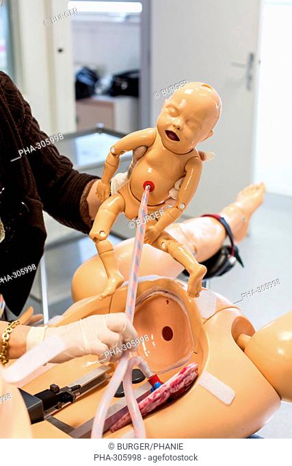 Student midwife delivering a baby mannequin from an adult mannequin, Both mannequins are equipped with sensors, sound and other devices designed to simulate...