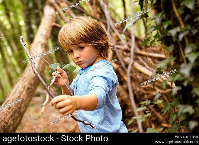 Boy playing with bow and arrow in forest