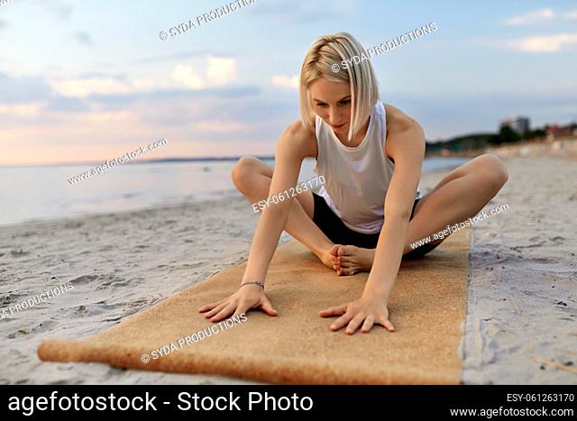 woman doing yoga stretching pose on beach