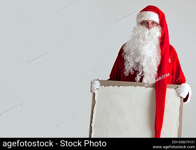 Santa Claus holding vintage paper billboard with copy space for text on gray background