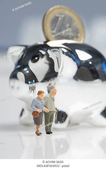 Senior couple figurines besides piggy bank with euro coin
