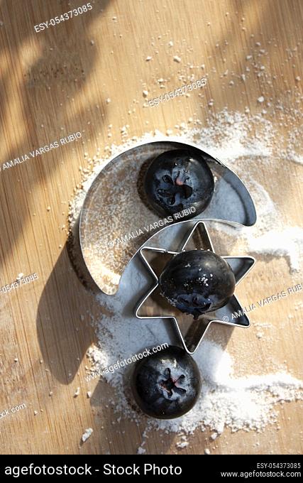 Blueberries eaten between moon and star figures that pose on sugar-free sweet granules for dessert