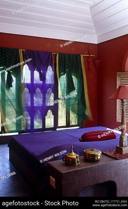 Double bed with purple cover in ethnic style red bedroom