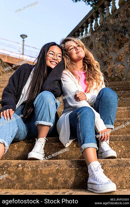 Young female friends sitting on staircase
