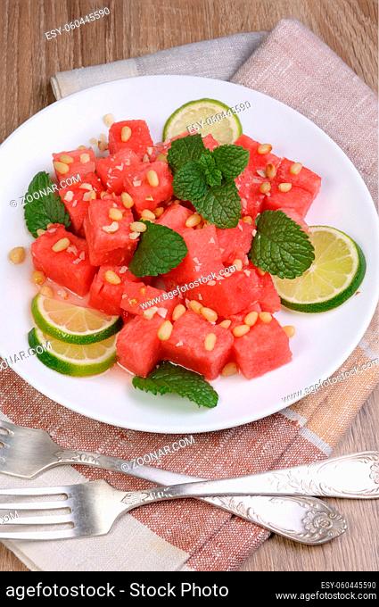 A refreshing salad of watermelon cubes with slices of lime, mint, peanuts, pine nuts