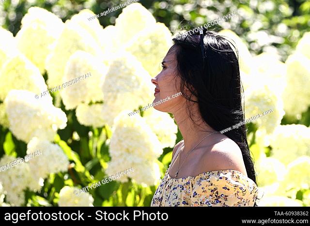 RUSSIA, MOSCOW - AUGUST 7, 2023: A woman poses for a photo by a blooming plant in Manezhnaya Square. Artyom Geodakyan/TASS