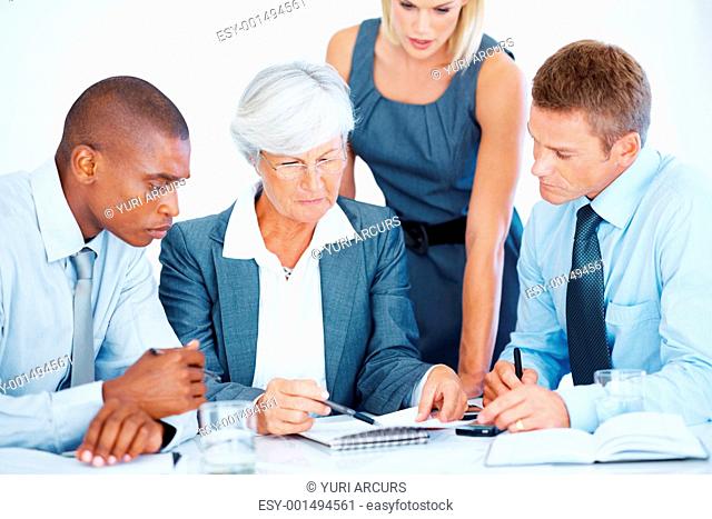 Female leader with multi ethnic team reviewing documents during meeting