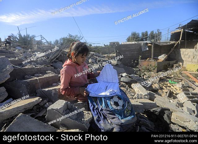 16 December 2023, Palestinian Territories, Rafah: Palestinian girl Ruaa Thaer Barhoum, 9 years old, searches for her school bag among the rubble of her house
